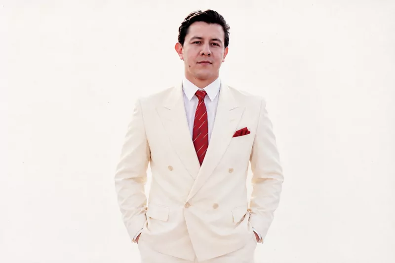 Imitador de José José con traje crema y corbata roja — estilo elegante diurno